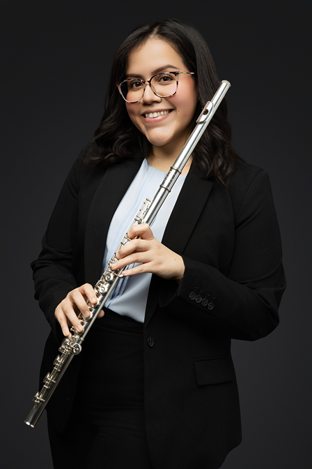 professional headshot of young alumna Isla Coronado in business attire holding a flute with dark background